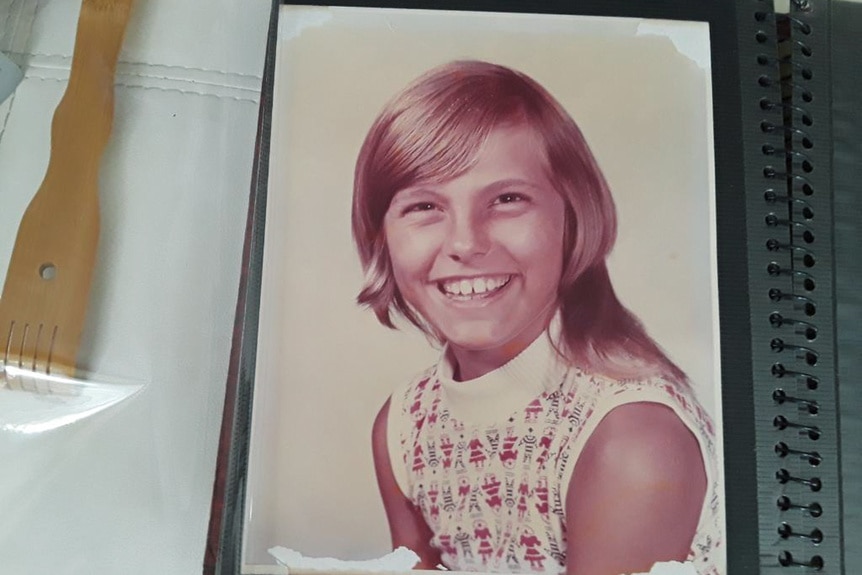 A childhood photo of Captain Sandy Yawn smiling inside of a photo book