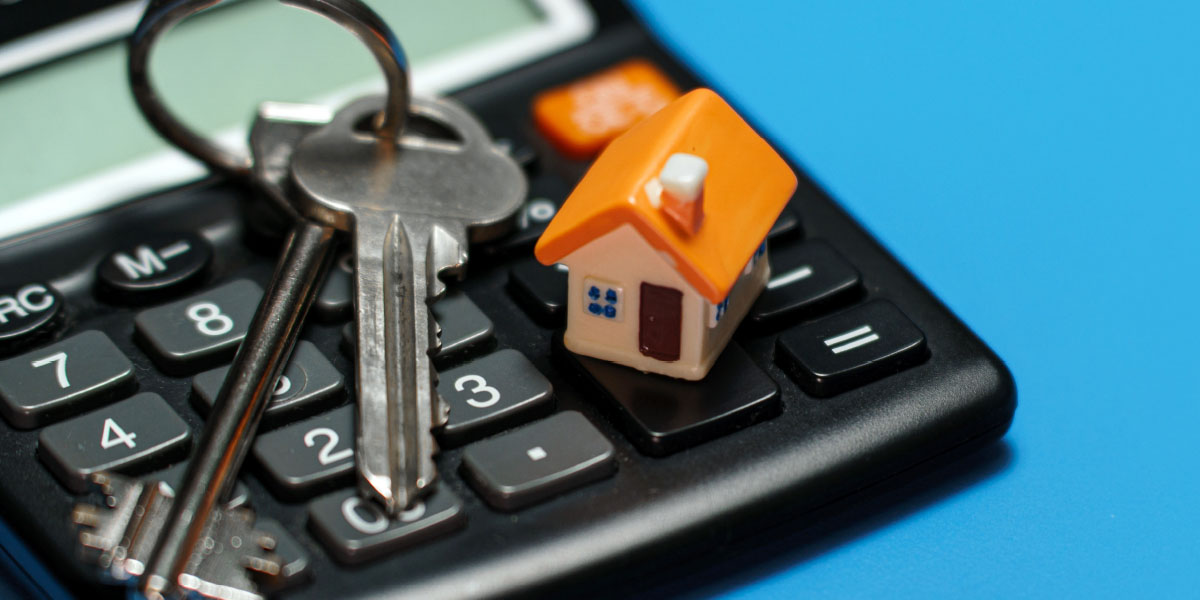 keys and a model of a house on top of a calculator