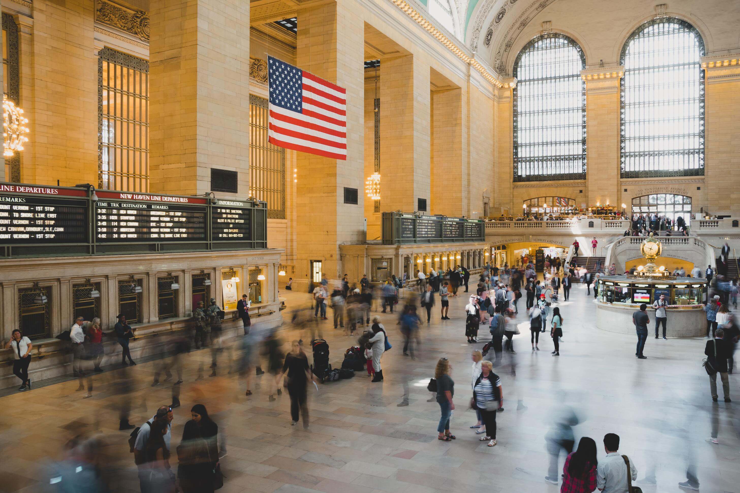 background piture shows a train station where many people walk around