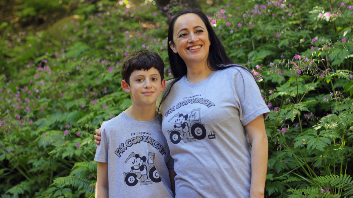 Child and woman wearing grey "Fix Copyright" t-shirts in a forest.