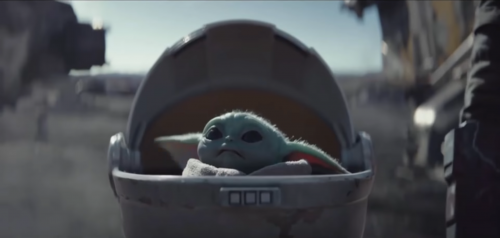 A tiny green baby yoda in a floating bassinet