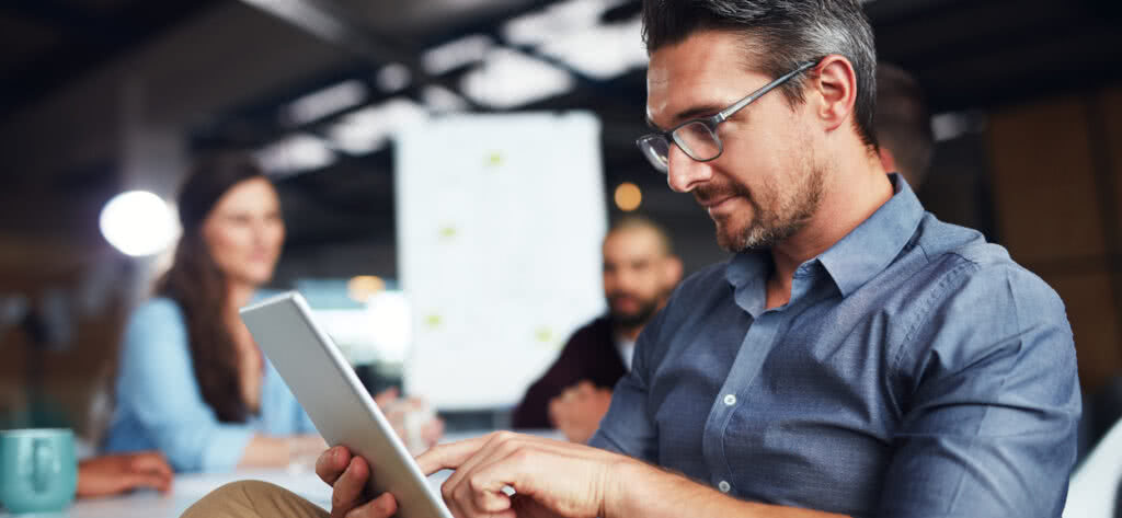 Man takes minutes on laptop at meeting.