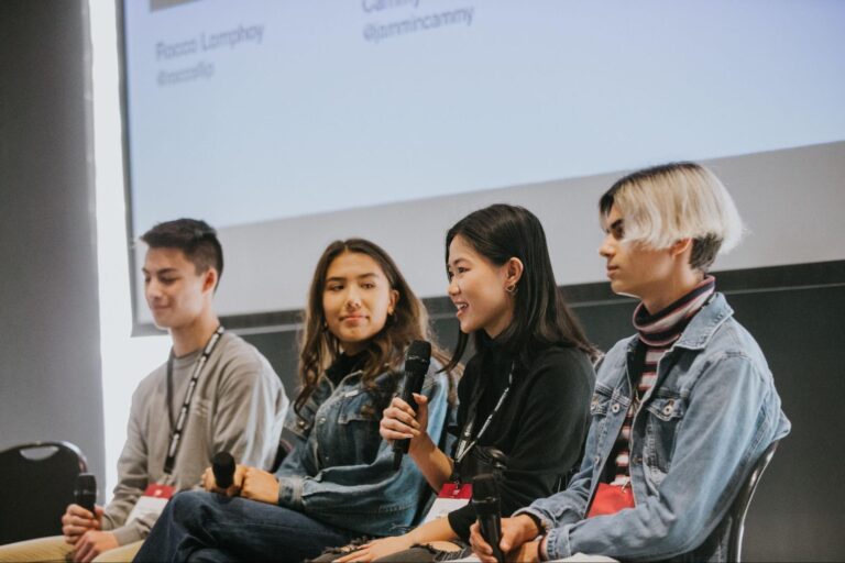 A group of speakers sit on stage at an event