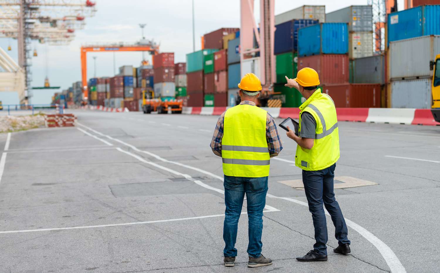 Two shipyard workers hurry to finish loading a cargo ship before a tariff is initiated.