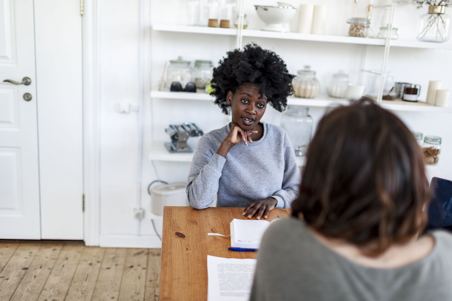 Woman sitting at a table talking to another woman