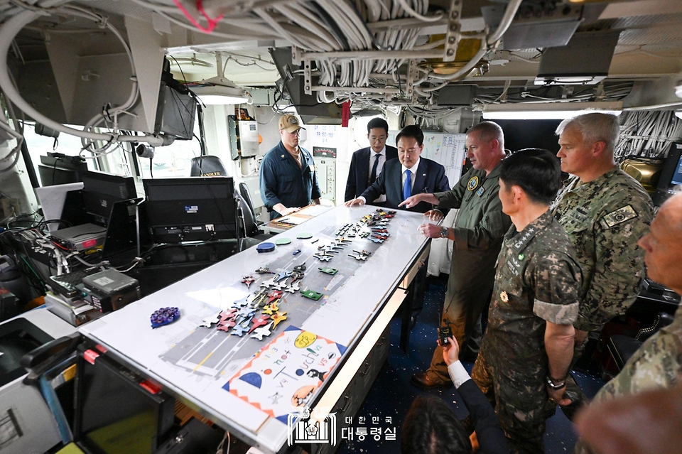 윤석열 대통령이 25일 부산 해군작전기지에서 미 해군 항공모함 시어도어 루즈벨트함에 승선해 비행갑판 통제실에서 브라이언 스크럼 루즈벨트 함장으로부터 항모에 대한 설명을 듣고 있다.