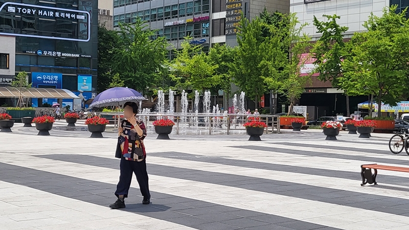 양산을 쓰고 햇빛을 가리며 걷는 시민.