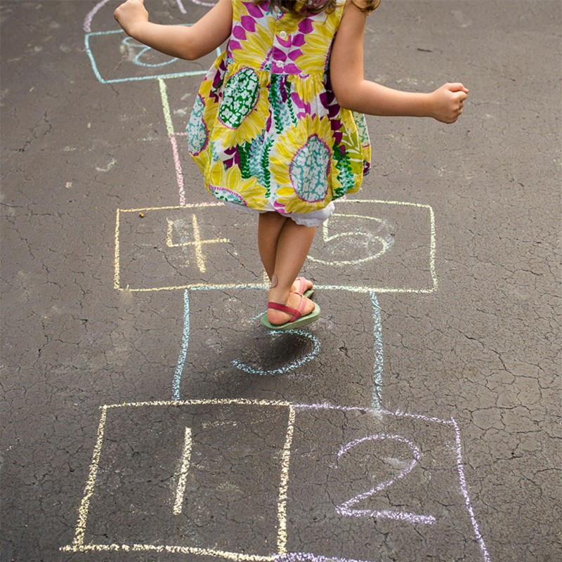 A child playing hopscotch on pavement.