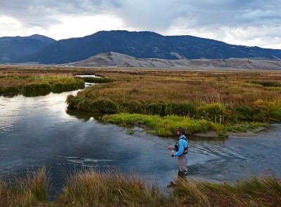 A man standing in a river fly-fishing.