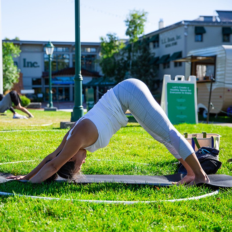 Woman practicing yoga outside on a mat.