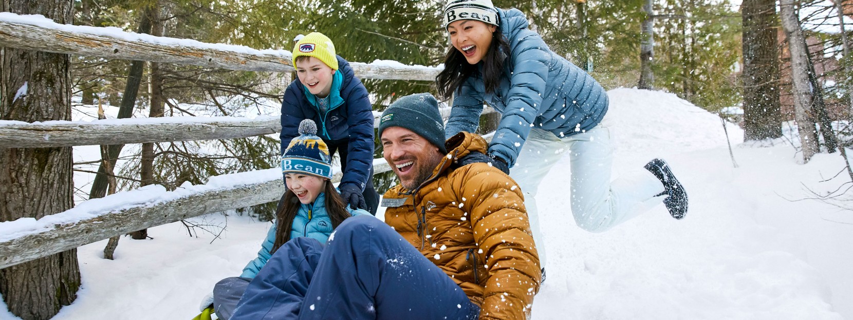 Two people sledding and two people pushing them