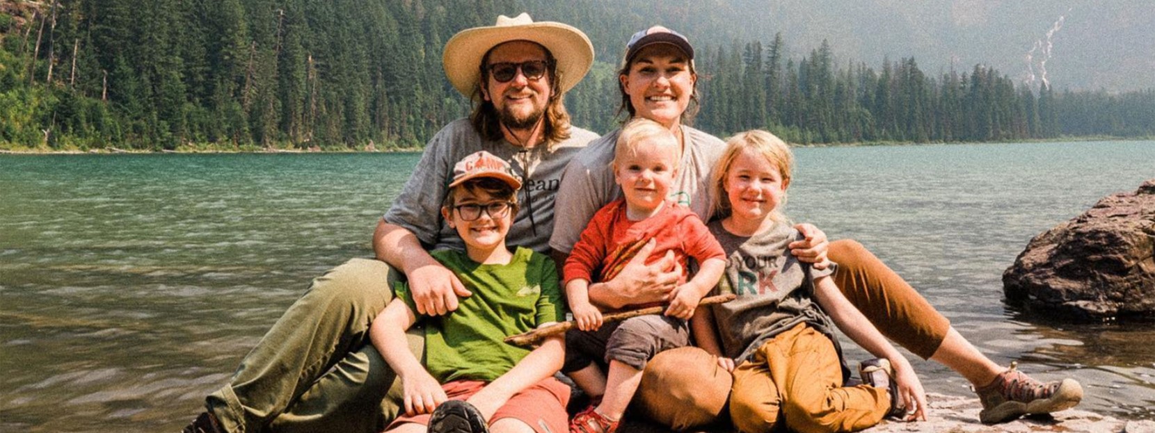 The Bowman Family sitting at waters edge in a national park.