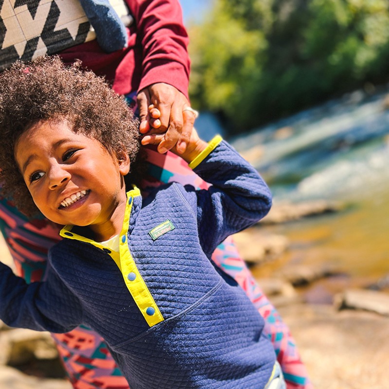 One of the Brooks children holding Shantel's hand by a river.