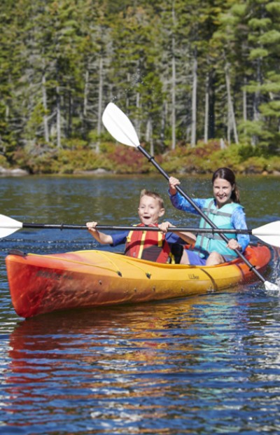 Mother and son kayaking on a lake with pinetrees in the background