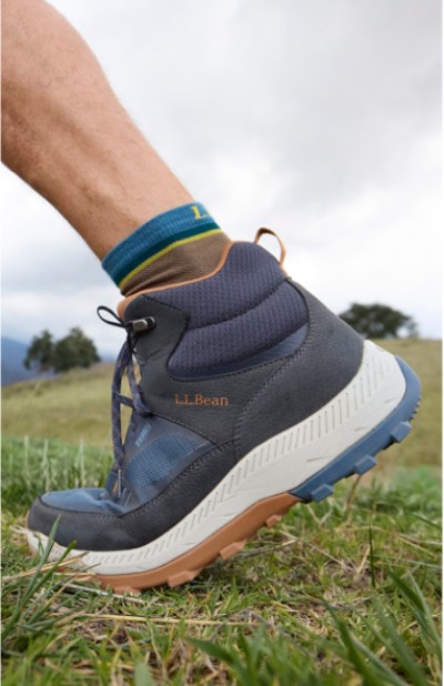 Image depicting a man wearing boots walking through a grassy field.