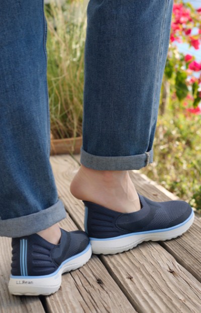 Image depicting a woman standing on a wooden deck with flowers in the background.