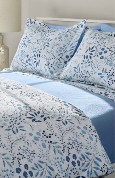 A bed with floral patterned bedding in shades of blue and white, creating a cozy and inviting atmosphere. 