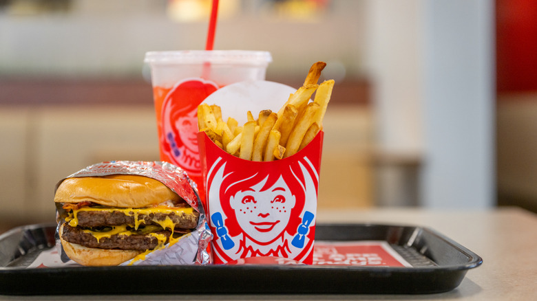 A Wendy's burger, fries, and a drink are on a tray.