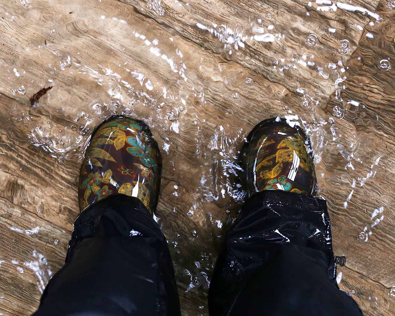 A home flooded with water with a homeowner standing in boots.