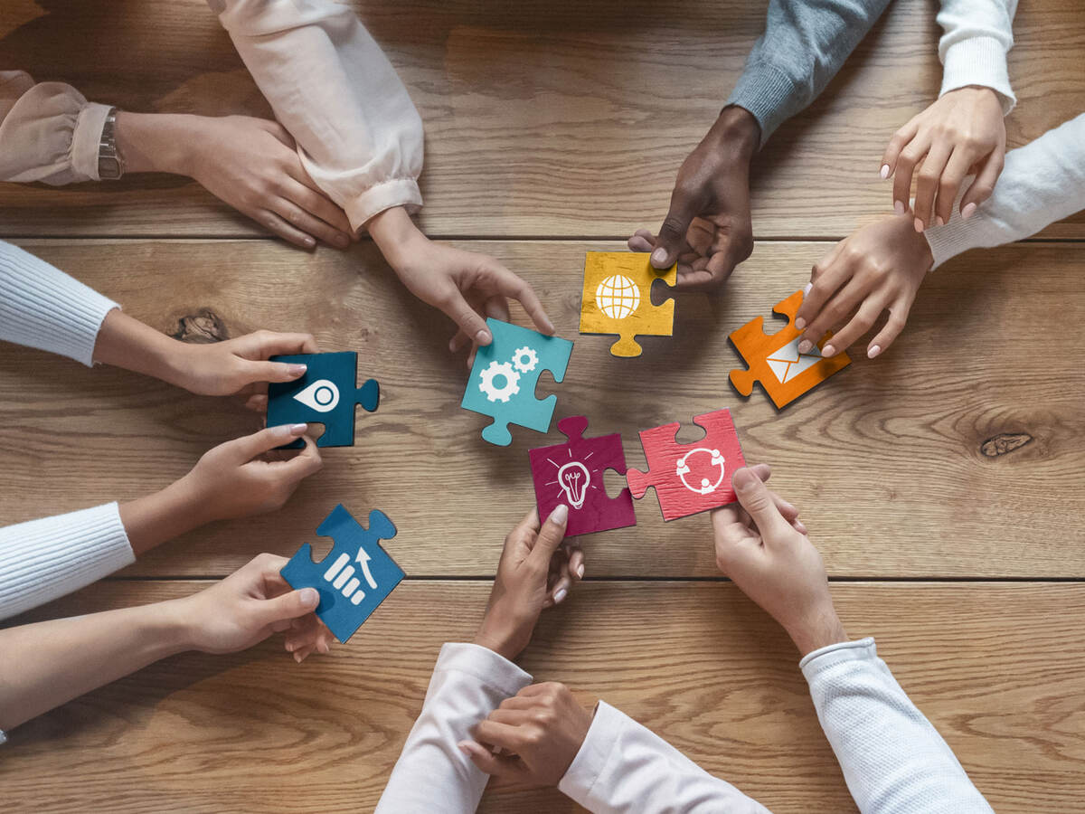 people around a table holding large puzzle pieces