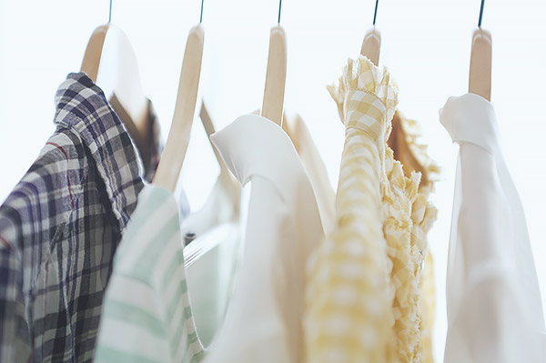 Five dress shirts with collars hanging on wooden hangers.