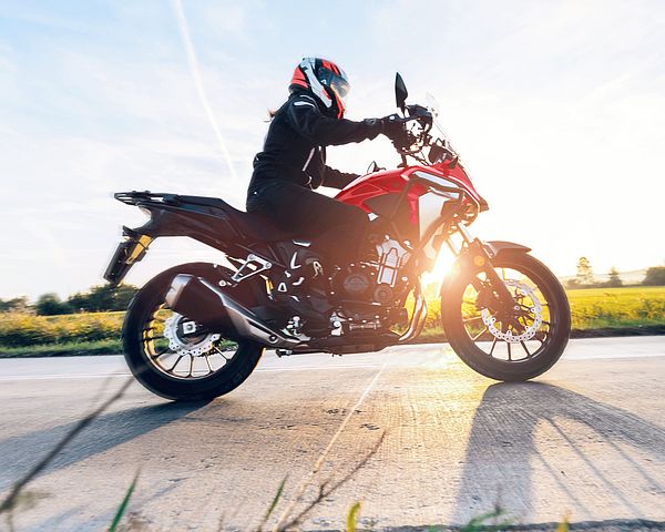 Ein Motorradfahrer fährt auf einer Straße bei Sonnenuntergang.