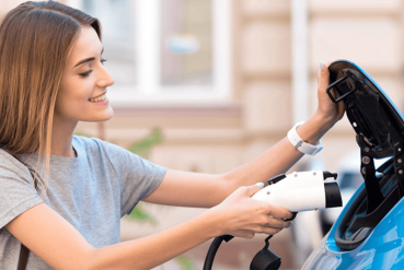 Femme branchant un cordon de recharge à son véhicule électrique