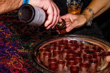 hand pouring a sample beverage into a small cup