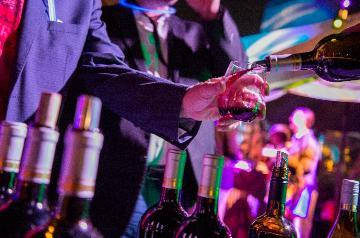 bartender pours red wine for person in a suit