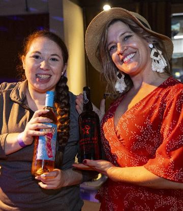 Two people smiling and holding a bottle of rose 