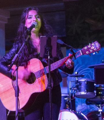 guitarist singing at mic lit by blue light