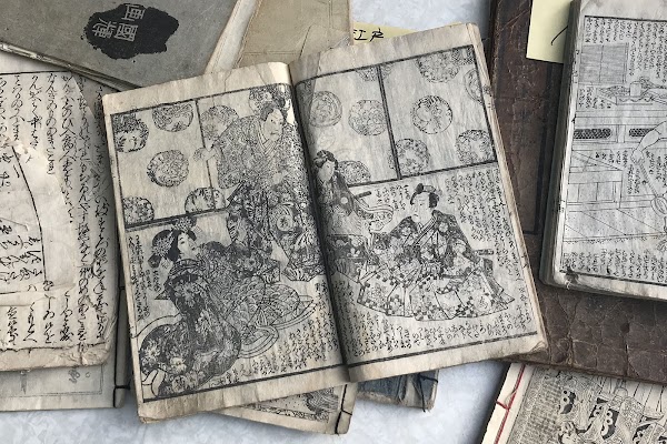 Several ancient Japanese manuscripts with illustrations scattered on a table.